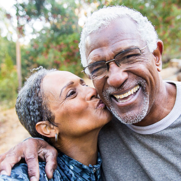 senior woman kissing partner on cheek and taking a selfie